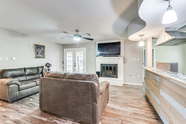 living room with french doors, light hardwood / wood-style floors, a fireplace, and ceiling fan