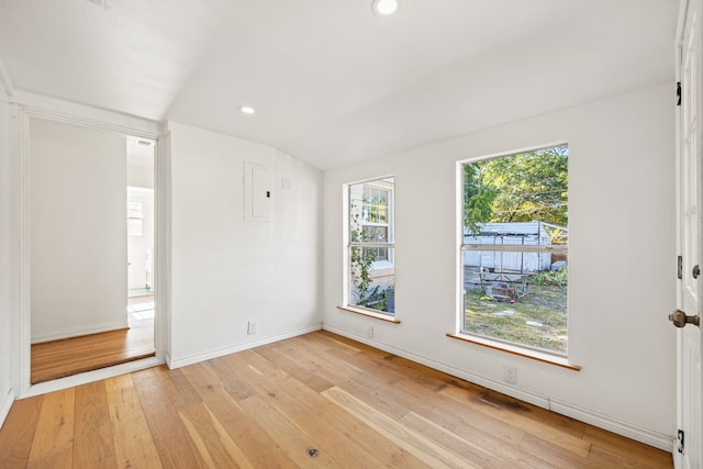 empty room with light hardwood / wood-style flooring and lofted ceiling