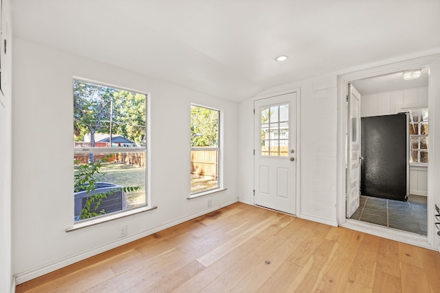 doorway with lofted ceiling and light wood-type flooring