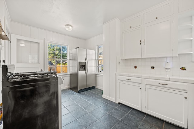 kitchen featuring tasteful backsplash, black stove, white cabinetry, tile counters, and stainless steel fridge with ice dispenser