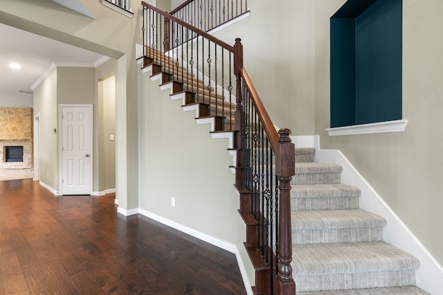 stairs featuring crown molding, a fireplace, and hardwood / wood-style floors