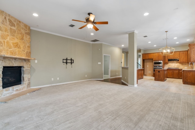 unfurnished living room with light carpet, a fireplace, ceiling fan with notable chandelier, and ornamental molding