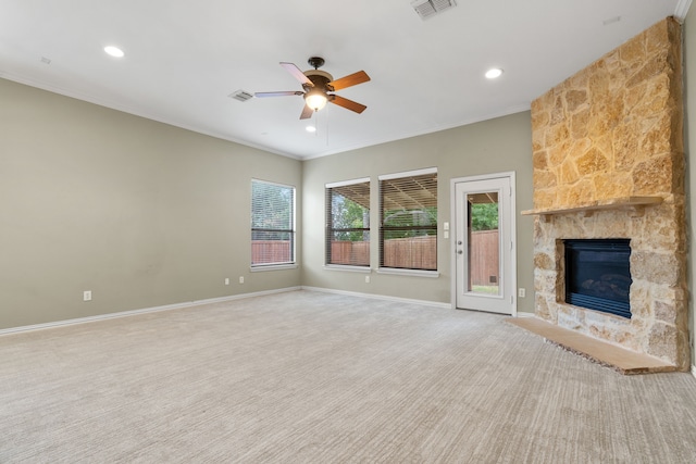 unfurnished living room with carpet flooring, a stone fireplace, ceiling fan, and ornamental molding