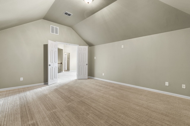 additional living space featuring light carpet and vaulted ceiling