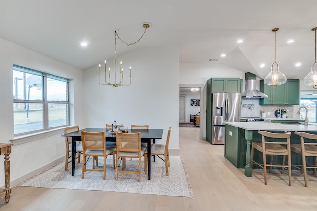 dining space featuring lofted ceiling, sink, light hardwood / wood-style flooring, and a chandelier