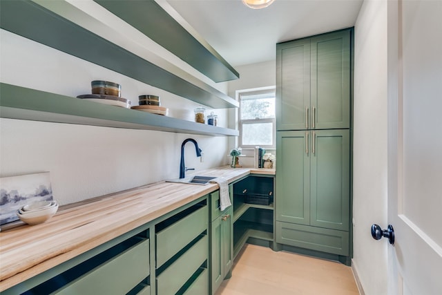 kitchen with sink, light hardwood / wood-style flooring, wooden counters, and green cabinetry