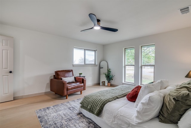 bedroom featuring a ceiling fan, visible vents, light wood finished floors, and baseboards