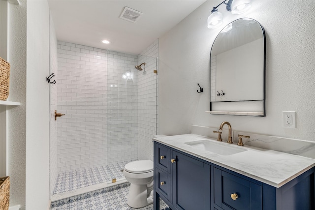 bathroom with vanity, toilet, and a tile shower