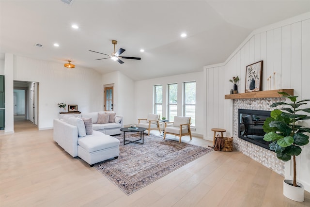 living room with ceiling fan, wooden walls, light hardwood / wood-style floors, and vaulted ceiling