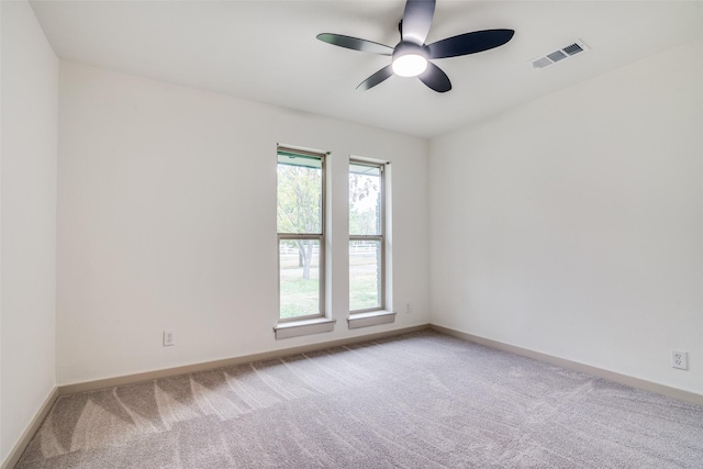 carpeted spare room featuring visible vents, ceiling fan, and baseboards