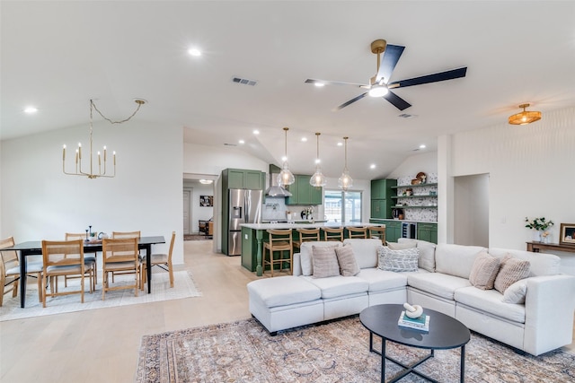 living room with ceiling fan with notable chandelier, lofted ceiling, and light hardwood / wood-style flooring