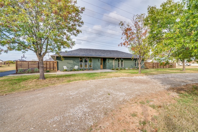 view of front of home with roof with shingles, fence, and a front yard