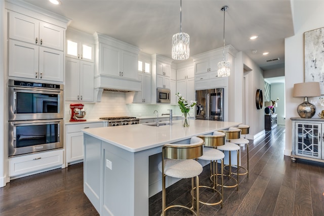 kitchen featuring white cabinets, stainless steel appliances, a center island with sink, and dark hardwood / wood-style flooring