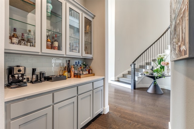 bar with gray cabinetry, dark wood-type flooring, and backsplash