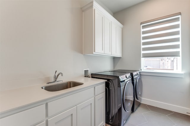 laundry room featuring light tile patterned flooring, cabinets, sink, and washing machine and clothes dryer