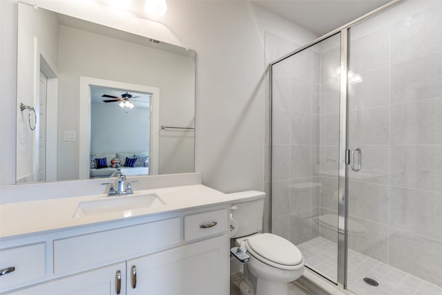 bathroom featuring vanity, toilet, a shower with door, and ceiling fan