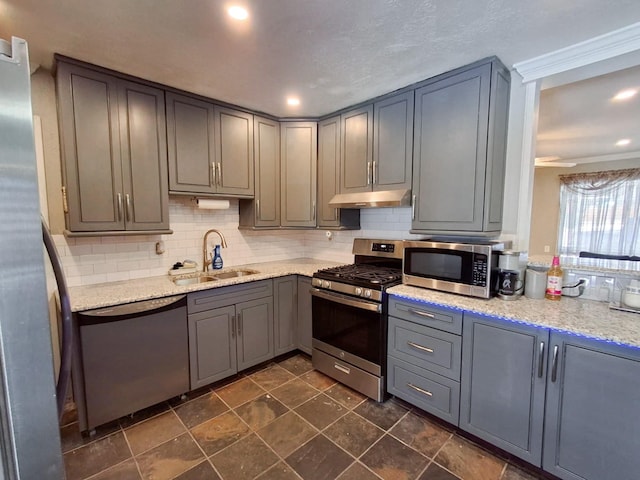 kitchen featuring light stone countertops, appliances with stainless steel finishes, tasteful backsplash, gray cabinetry, and sink