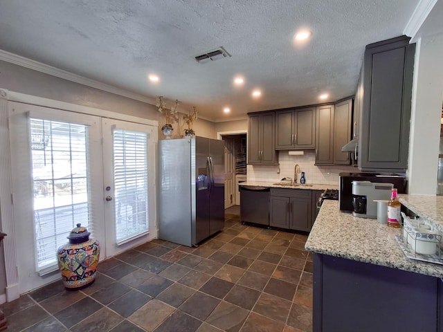 kitchen featuring gray cabinetry, light stone counters, a textured ceiling, decorative backsplash, and appliances with stainless steel finishes