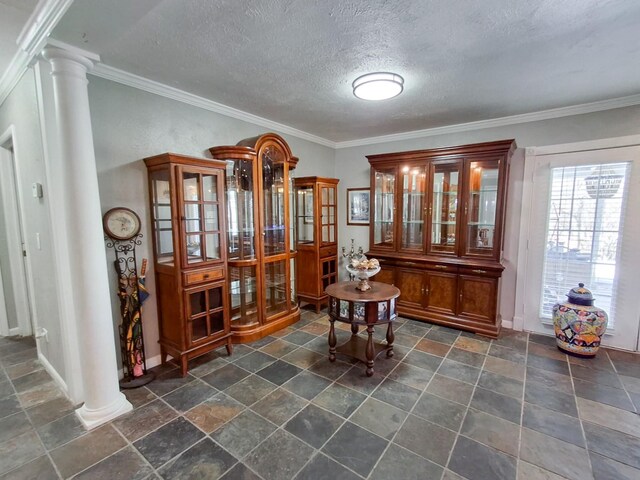 interior space featuring a textured ceiling, ornate columns, and crown molding