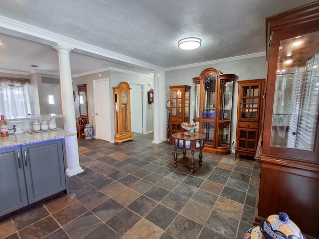 interior space featuring crown molding, ornate columns, and a textured ceiling