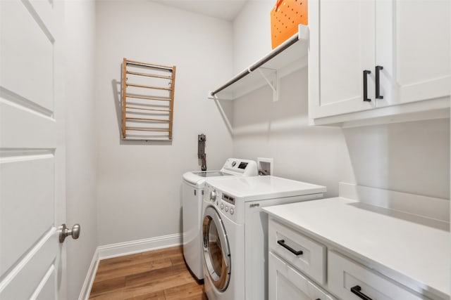 laundry room with cabinet space, washer and dryer, light wood finished floors, and baseboards