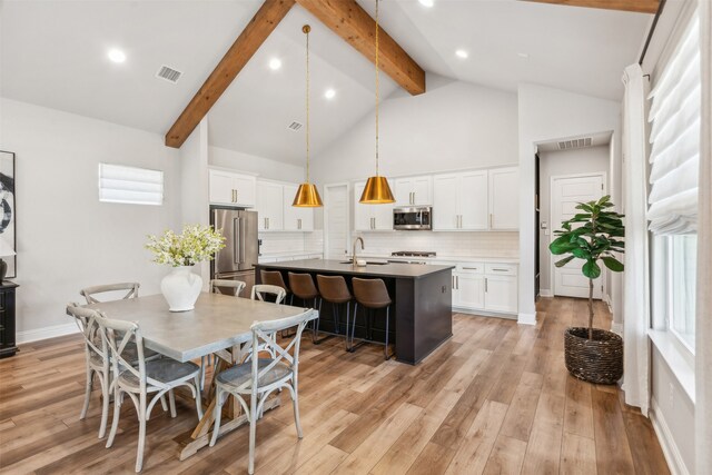 dining space with beam ceiling, light wood-style flooring, visible vents, and high vaulted ceiling