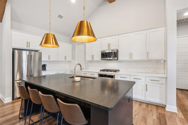 kitchen with visible vents, light wood finished floors, a sink, stainless steel appliances, and white cabinets