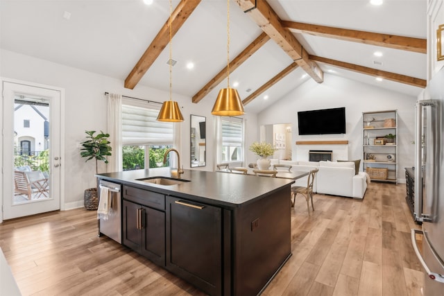 kitchen featuring a glass covered fireplace, a sink, dishwasher, dark countertops, and light wood-type flooring