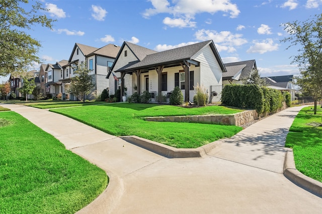 view of front of property featuring brick siding, a front lawn, fence, a residential view, and roof with shingles