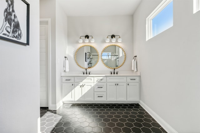 full bath featuring double vanity, baseboards, and a sink