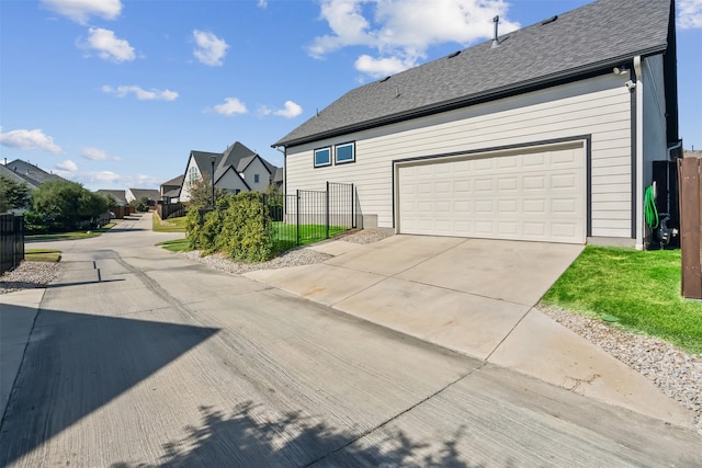 view of property exterior with fence, a garage, and a shingled roof