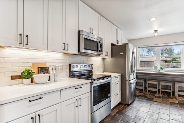 kitchen featuring white cabinetry, stainless steel appliances, decorative backsplash, and a textured ceiling