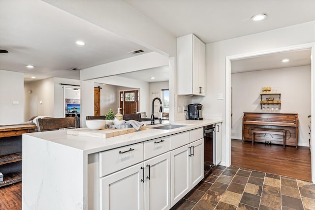 kitchen with kitchen peninsula, sink, white cabinets, black dishwasher, and decorative backsplash