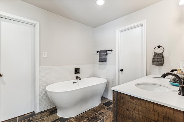 bathroom featuring vanity, tile walls, and a bathtub