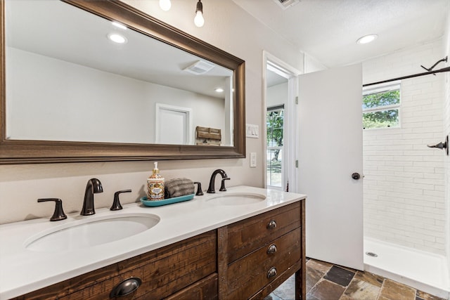 bathroom with vanity and tiled shower