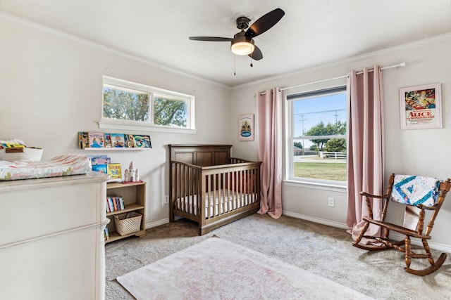 carpeted bedroom featuring a crib, ornamental molding, and ceiling fan