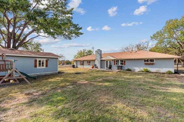 back of house featuring a playground, a lawn, and a patio area