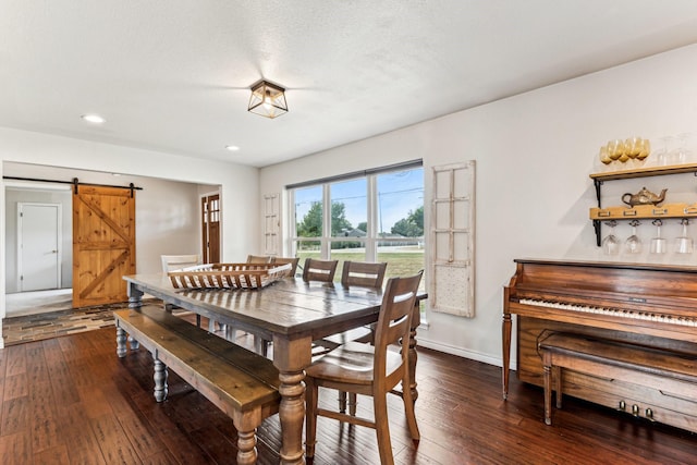 dining space with a barn door, a textured ceiling, and dark hardwood / wood-style flooring