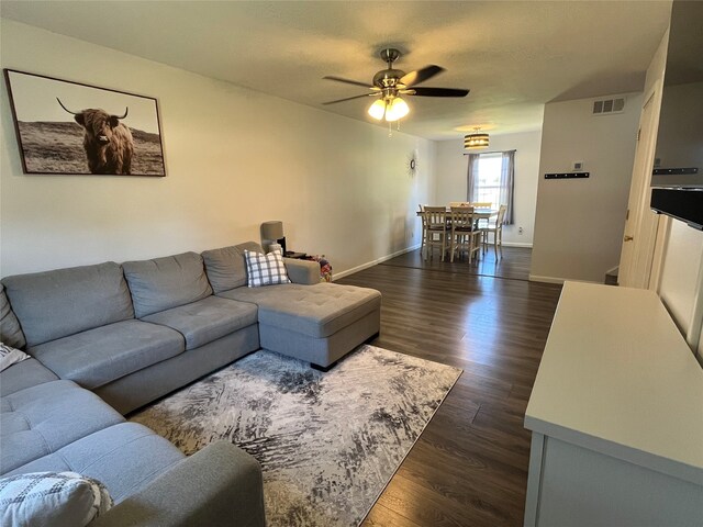 living room featuring ceiling fan and dark hardwood / wood-style flooring