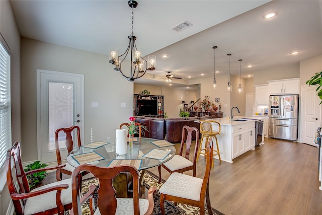 dining room featuring light hardwood / wood-style floors, sink, and ceiling fan with notable chandelier