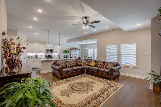 living room featuring sink, dark hardwood / wood-style floors, and ceiling fan with notable chandelier