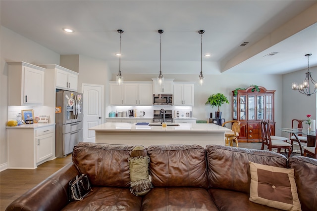 kitchen featuring appliances with stainless steel finishes, pendant lighting, white cabinets, dark wood-type flooring, and a notable chandelier