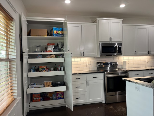 kitchen with white cabinetry, tasteful backsplash, appliances with stainless steel finishes, and dark stone countertops