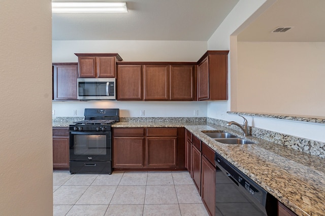 kitchen featuring light stone counters, sink, light tile patterned floors, and black appliances