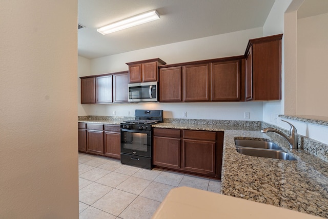 kitchen with light tile patterned flooring, black range with gas stovetop, light stone countertops, and sink