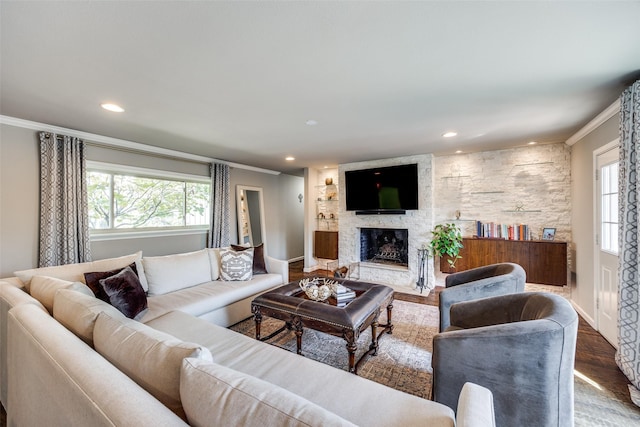 living room featuring hardwood / wood-style flooring, plenty of natural light, ornamental molding, and a fireplace