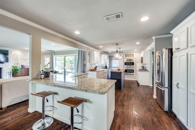 kitchen featuring white cabinets, dark hardwood / wood-style floors, ornamental molding, appliances with stainless steel finishes, and kitchen peninsula