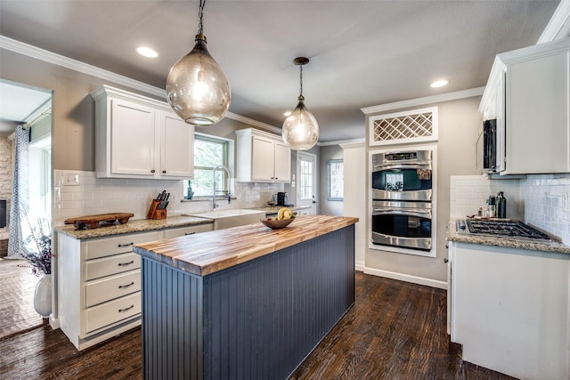 kitchen featuring pendant lighting, wooden counters, dark hardwood / wood-style floors, a kitchen island, and white cabinetry