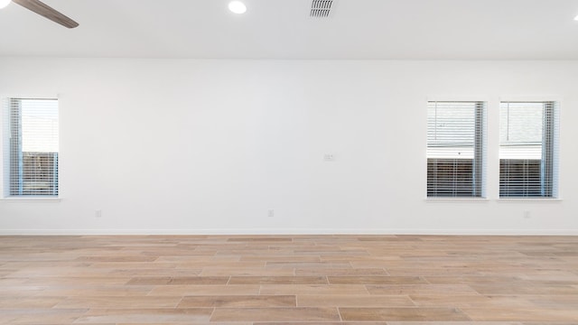 empty room with ceiling fan and light hardwood / wood-style floors