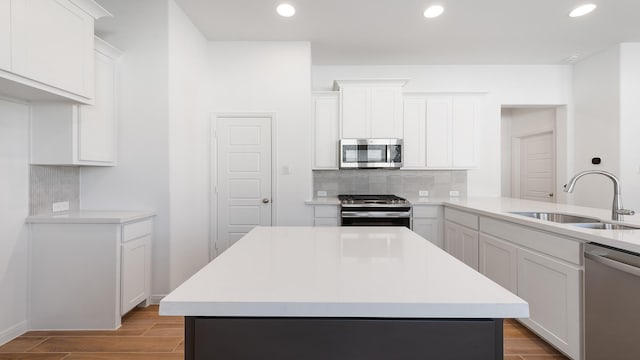 kitchen with appliances with stainless steel finishes, sink, a kitchen island, and white cabinets